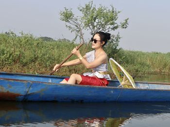 Young woman sitting on boat against lake