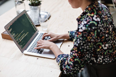 Midsection of businesswoman using laptop at table in office