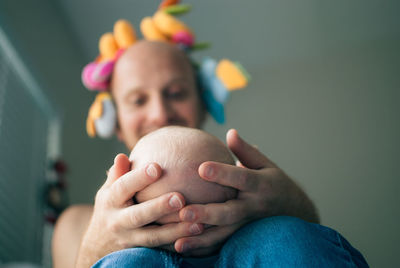 Close-up of man holding baby in hand while sitting at home