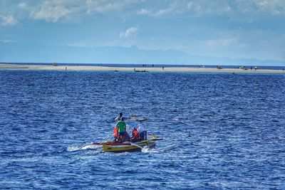 People on boat in sea against sky
