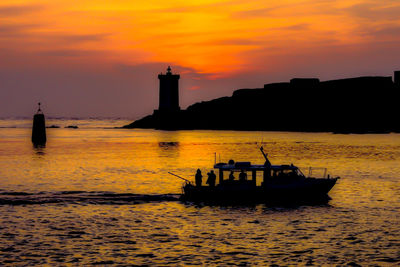 Boat sailing in sea against orange sky