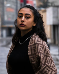 Portrait of young woman standing against wall