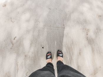 Low section of person standing on sand