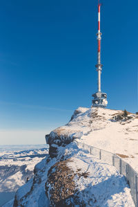 Tower on snowcapped mountain against clear blue sky