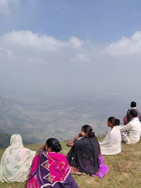 Rear view of people on landscape against sky