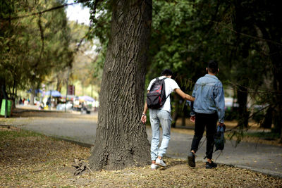 Rear view of couple walking on tree trunk