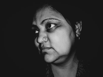 Close-up portrait of beautiful young woman over black background