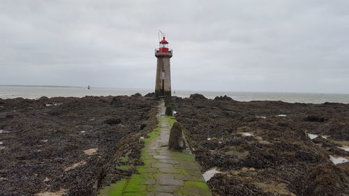 Lighthouse by sea against sky