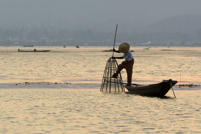 Fisherman fishing in lake during sunset