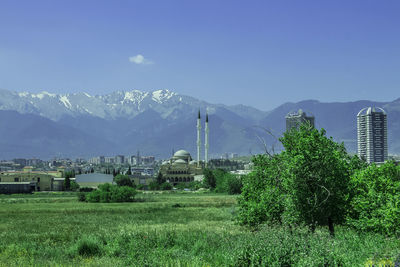 Scenic view of field by buildings against sky