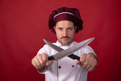 Portrait of man standing against red background