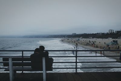 People by sea against clear sky