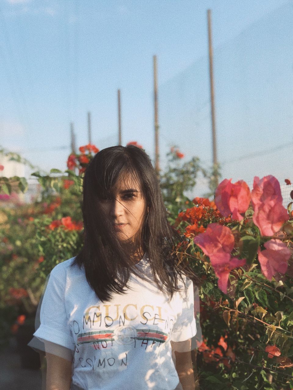 plant, flower, flowering plant, one person, front view, nature, standing, real people, casual clothing, young adult, day, lifestyles, portrait, leisure activity, focus on foreground, young women, waist up, hairstyle, long hair, outdoors, beautiful woman, bouquet, flower arrangement