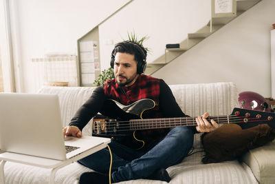 Full length of man playing guitar at home