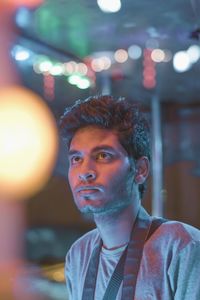Young man looking up against illuminated lights at night