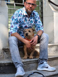 Low section of man with dog sitting on staircase