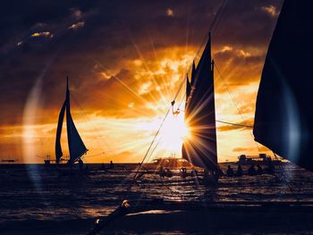 Sunlight streaming through sailboat on sea during sunset