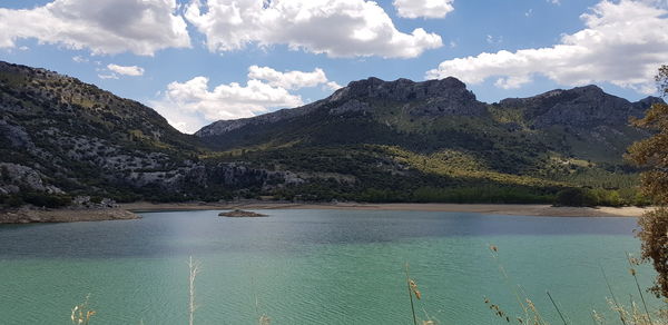 Scenic view of lake by mountains against sky