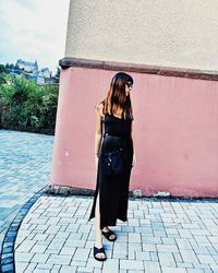 Full length of woman standing against wall