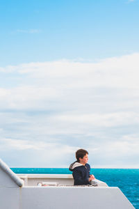 Full length of man sitting on sea against sky