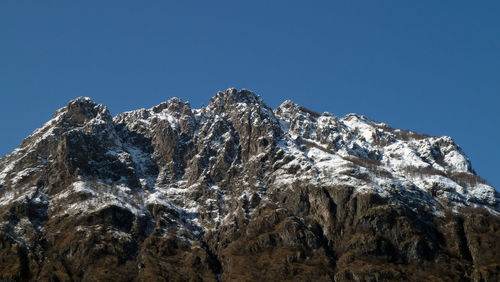 Low angle view of snowcapped mountain against clear blue sky