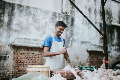 Happy butcher cutting meat at market stall