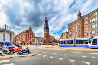 Low angle view of city street against cloudy sky