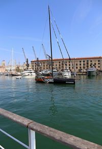 Sailboats moored at harbor against sky