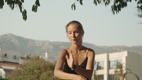 Portrait of young woman standing against mountain