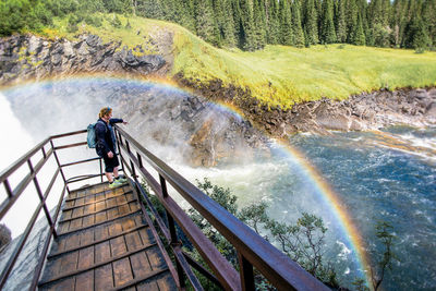 Man standing by railing in forest