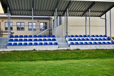 Empty chairs by swimming pool in field