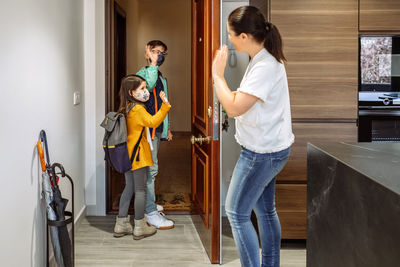 Sibling waving mother while walking through entrance