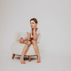 Young woman sitting against white background