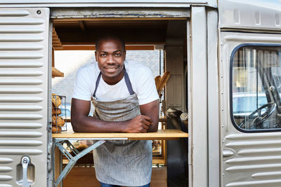 Portrait of confident mid adult male owner standing in food truck