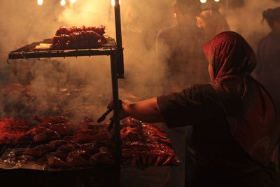 Rear view of man preparing food on barbecue grill