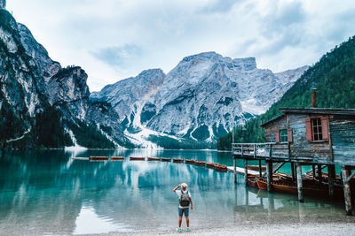 Rear view of person on lake by snowcapped mountains against sky