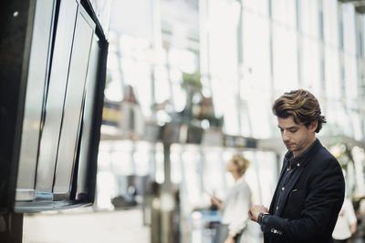 Businessman checking the time by arrival departure board at airport