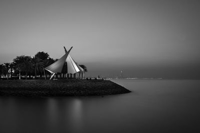 Traditional windmill by sea against clear sky