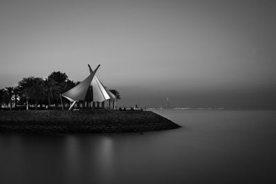 Traditional windmill by sea against clear sky