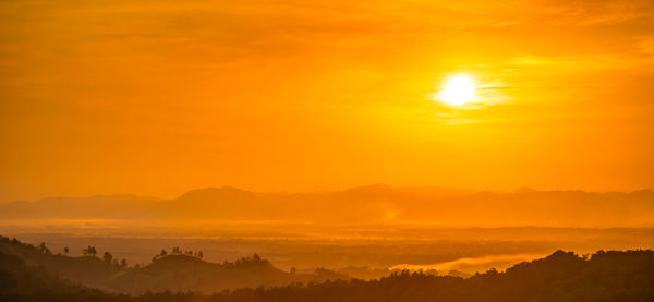 Scenic view of silhouette mountain against orange sky