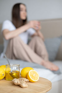 Lemons and ginger on table while woman sitting in background at home