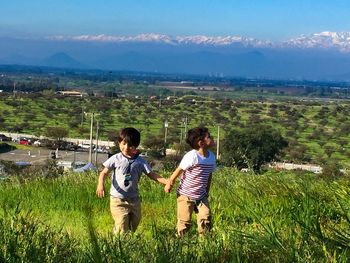 Boys standing on field against sky