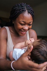 Loving african american mom cuddling and holding newborn baby while enjoying pleasant motherhood moments
