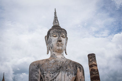 Low angle view of buddha statue against sky