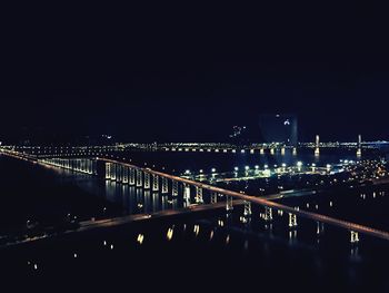 Illuminated bridge against clear sky at night