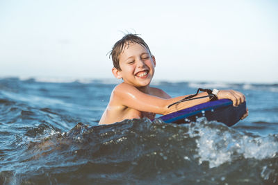 Smiling boy riding wakeboard in ocean