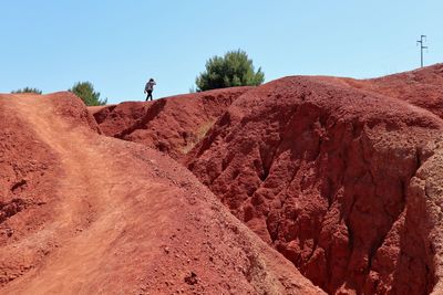 Man walking on rocks against clear sky