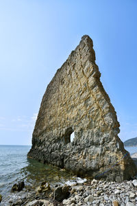 Rock formation in sea against clear blue sky