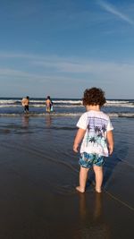Rear view of baby boy standing on shore at beach