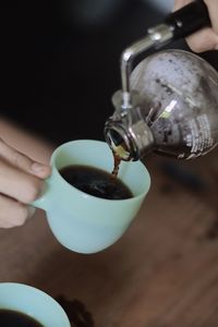 Close-up of hand pouring coffee cup